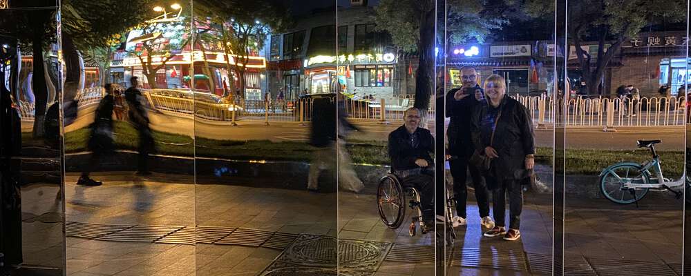 Nino, Julijana, and Zarino reflected in a large mirror, outdoors, at night time