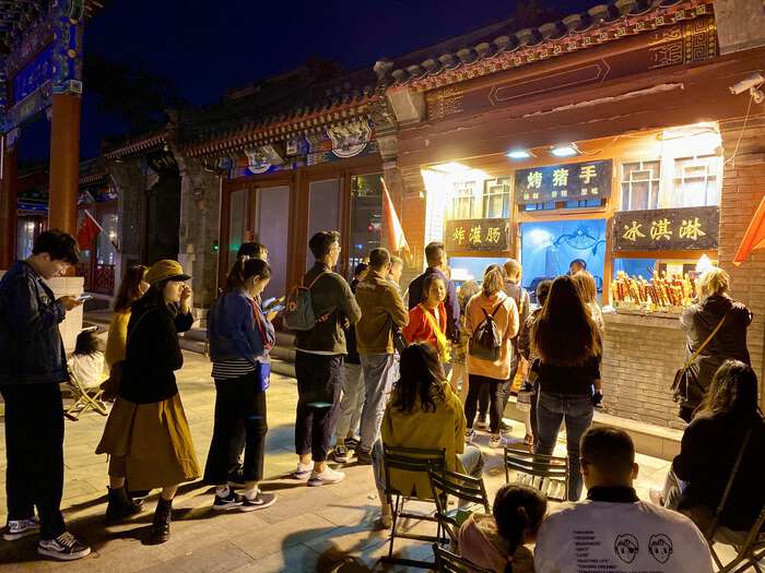 People waiting in a queue outside a food shop, at night