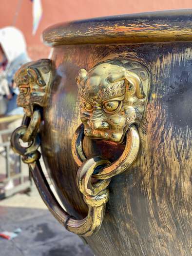 Lion head handles on the side of a large golden urn