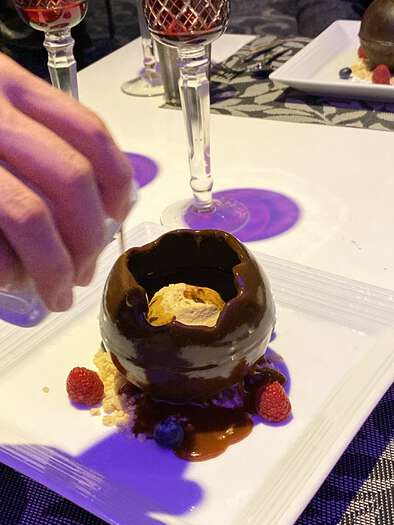 Chocolate sphere dessert being melted with warm sauce, 3 of 3