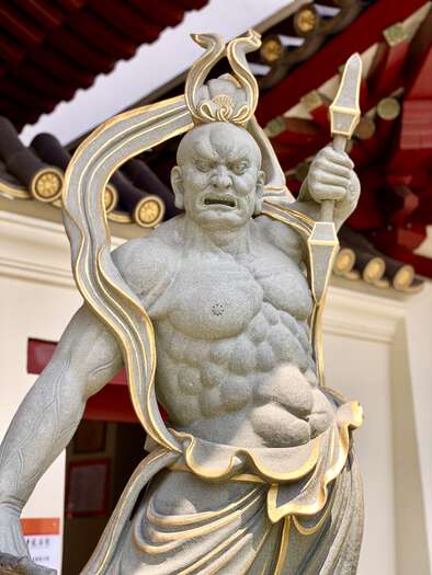An impressive statue of a muscular guardian outside the temple